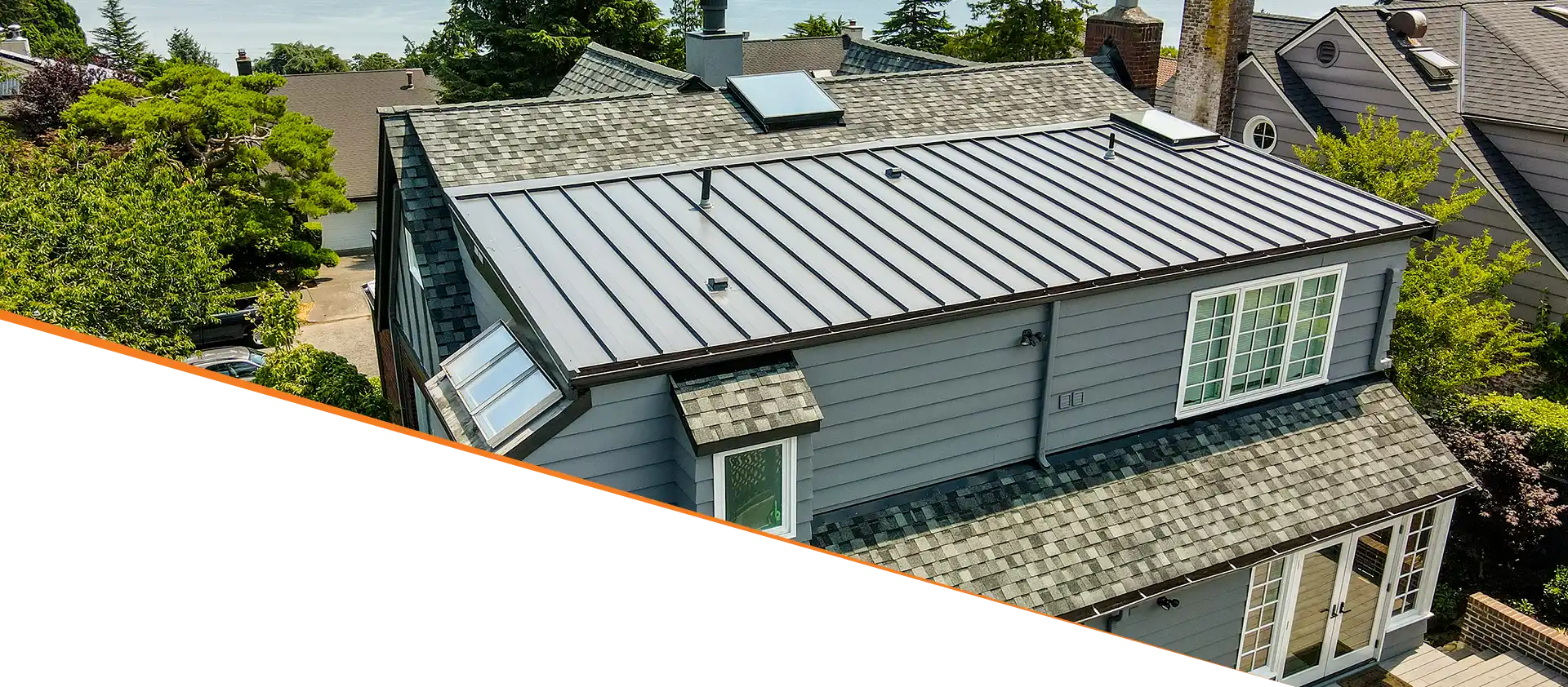 Aerial view of a house with a metal roof and skylights, showcasing the roof's design and material.