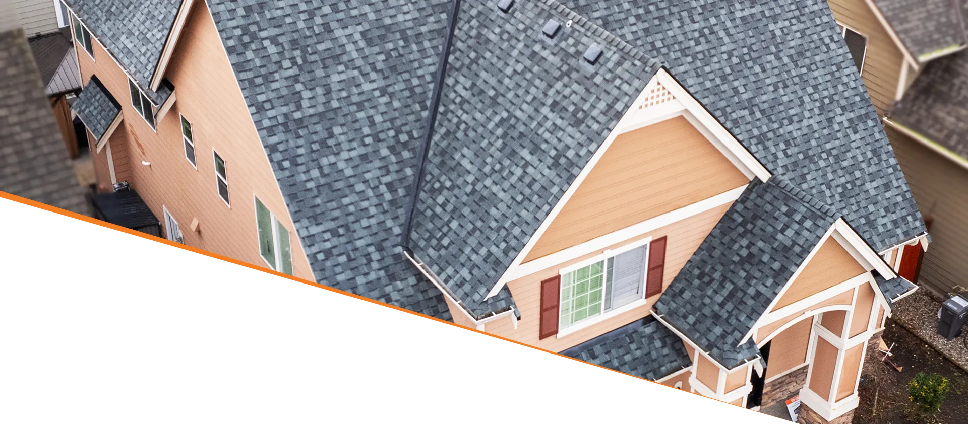An aerial view of a house with a gray shingle roof and beige siding.