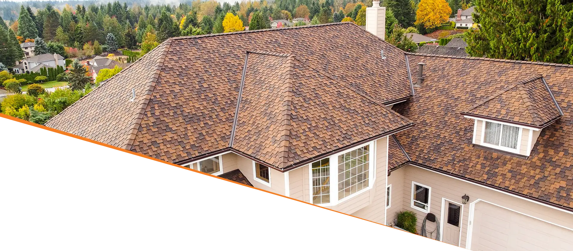 Aerial view of a house with a multi-colored shingle roof surrounded by trees and other homes.