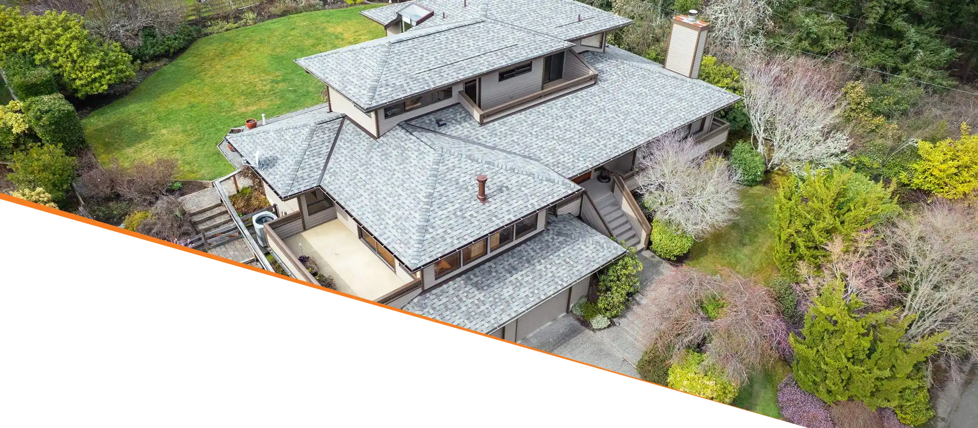 Aerial view of a large house with a unique architectural design, surrounded by greenery and landscaped gardens.