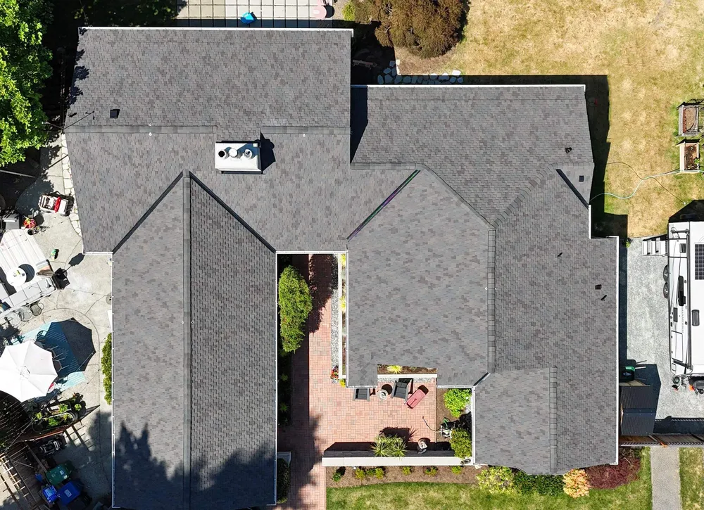 Aerial view of a residential home with a gray roof and a yard.
